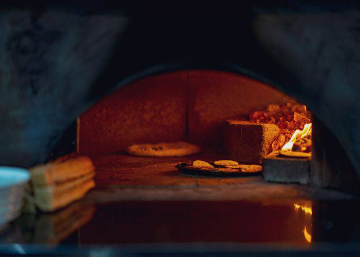 A pizza deep inside a pizza oven, cooking.