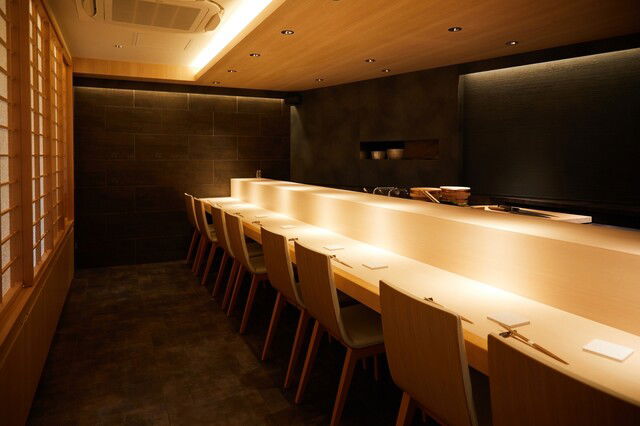 The high-end interiors of Shibuya Sushiki, featuring warm, wooden counter seating.