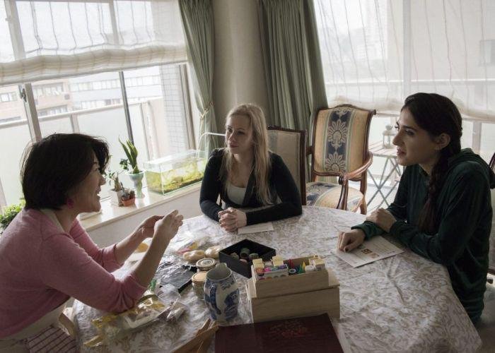 A Japanese woman shows two foreign women how to make delicious Japanese wagashi as they sit around a table together in a Japanese home