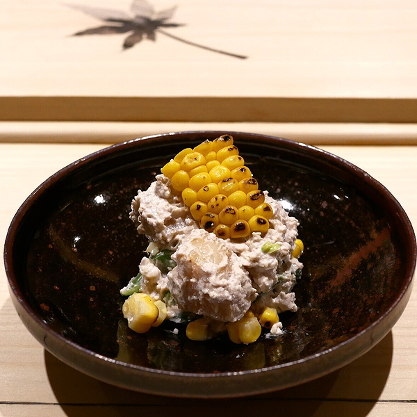 Exquisite corn and cream salad on a dark plate at a gourmet restaurant.