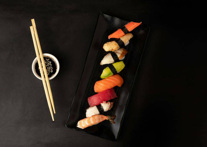 A top-down shot of different kinds of sushi on a black tray.