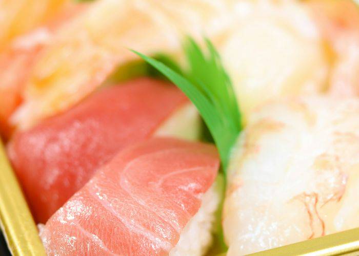 A tray of fresh nigiri sushi, showing off raw salmon on white rice.