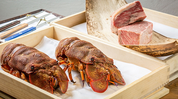 Fresh lobster and marbled steak on wooden trays in a restaurant setting