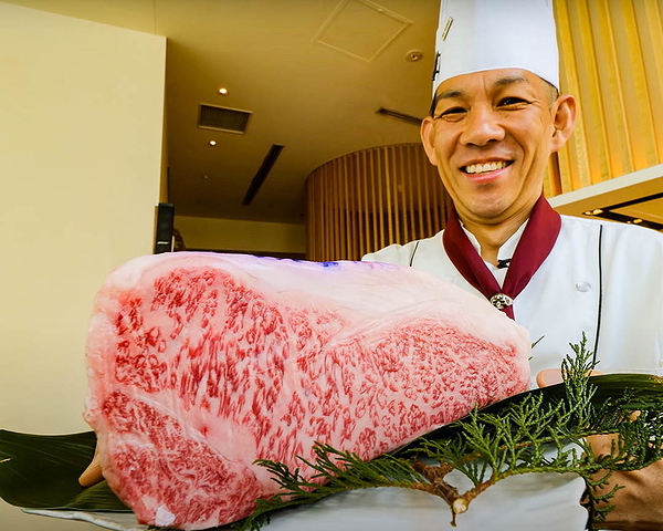 Chef presenting premium marbled Wagyu beef in gourmet setting