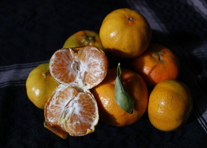 A pile of Japanese mikan, one peeled and split in half.