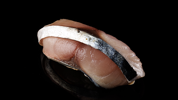 Elegant mackerel sushi piece on black background