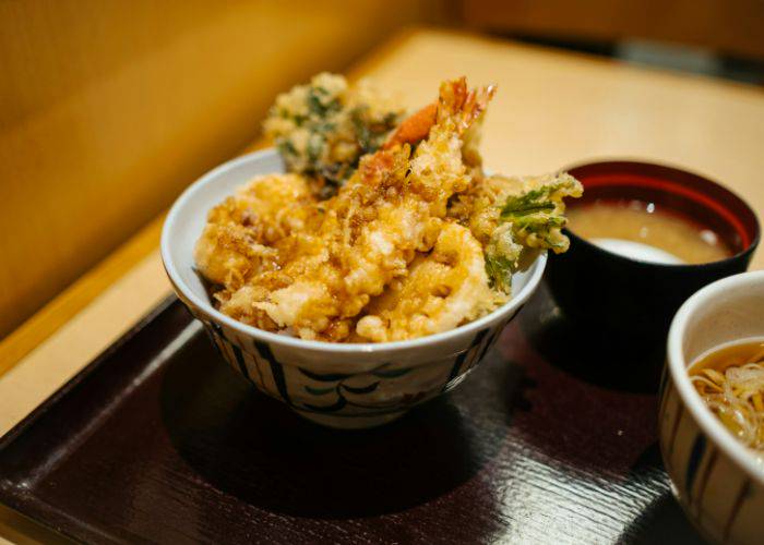 A bowl of crispy tempura, including shrimp tempura, on a bed of rice.