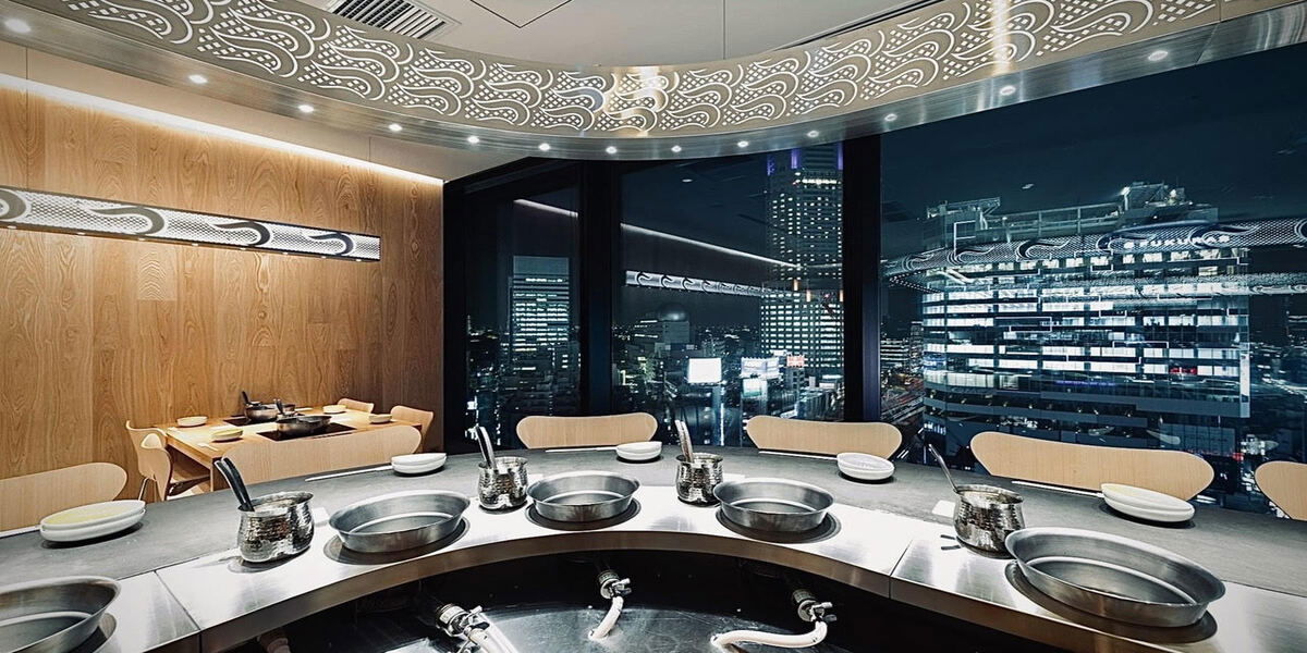 The curved counter seating of Shabu-Shabu Tsukada Shibuya Scramble Square, set against the skyline of Tokyo at night.