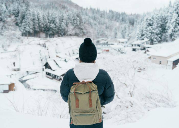 A person in warm, winter clothing, looking out at the snow-covered landscapes of Hokkaido.