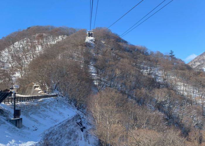 A cable car coming down from the top of a snowy mountain in Nikko.