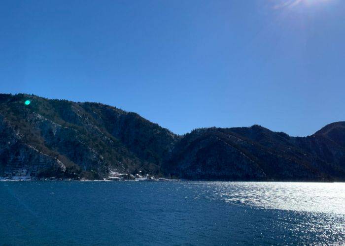 Lake Chuzenji on a clear, blue-sky day; the water sparkles with sunlight.