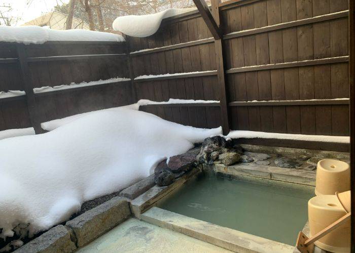 An outdoor hot spring bath of Yumoto Onsen, made even more magical by a thick layer of snow.