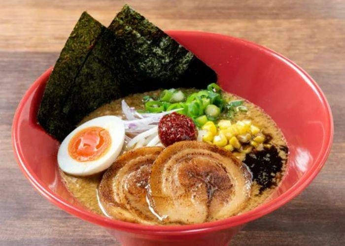 A bowl of Ippudo Ramen noodles, presented in their iconic red ramen bowl.