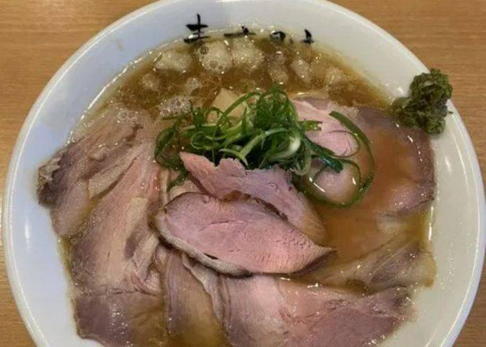 A generous portion of meat served atop fresh ramen at Muginoyoake.