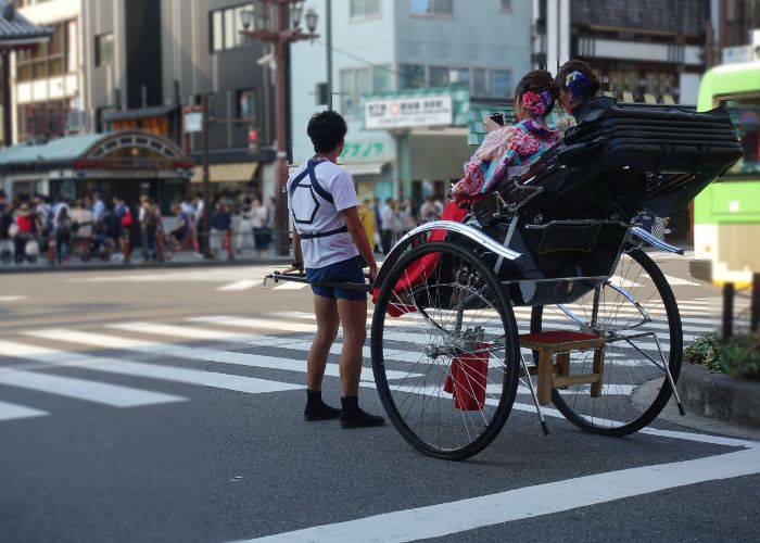 Two woman in kimono seeing Asakusa from the luxury of rickshaw transport.