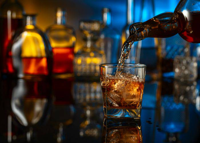 A glass of whiskey being poured at a stylish bar.