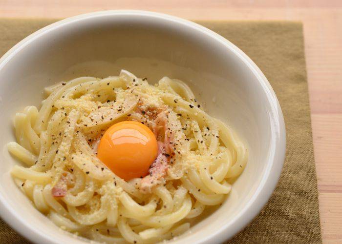 Carbonara udon at Menchirashi, famous for its creamy sauce and bright orange egg yolk.