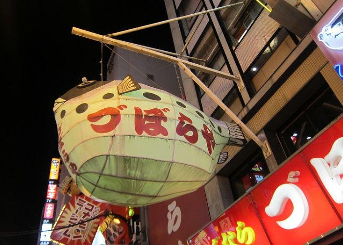 Exterior of Zuboraya (づぼらや) in Dotonbori, a well-known fugu restaurant in Osaka with a pufferfish lantern outside