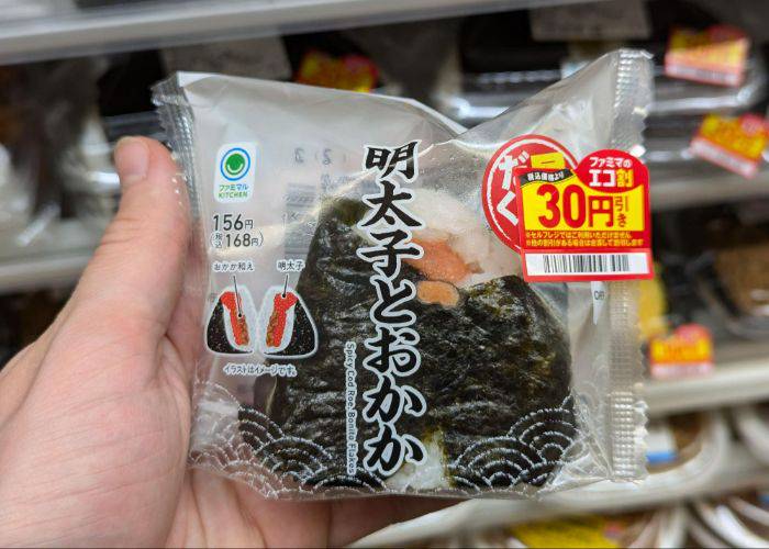 Kevin holding a mentaiko and bonito flake onigiri in the konbini.