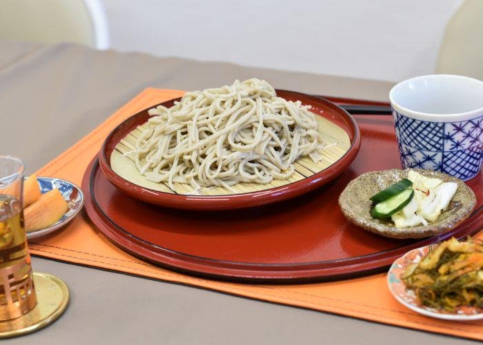 A plate of cold soba noodles, and small side dishes