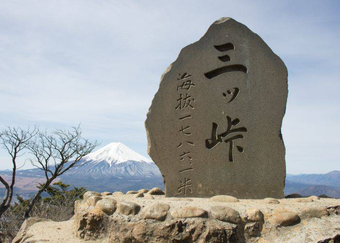 The peak of Mt. Mitsutoge, with a snow-capped Mt. Fuji in the background.