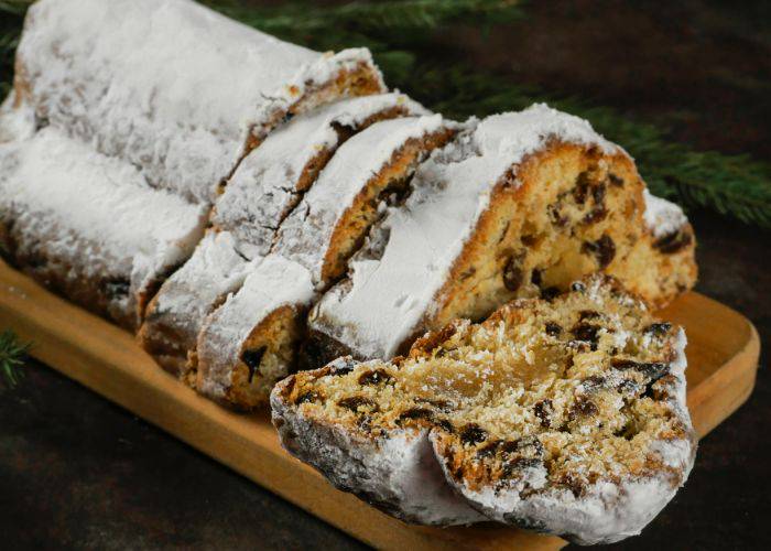 A fresh loaf of stollen, sliced and dusted with icing sugar.