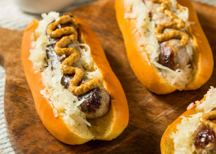 Bratwurst (German sausage) in a hotdog bun, served with onion and mustard.