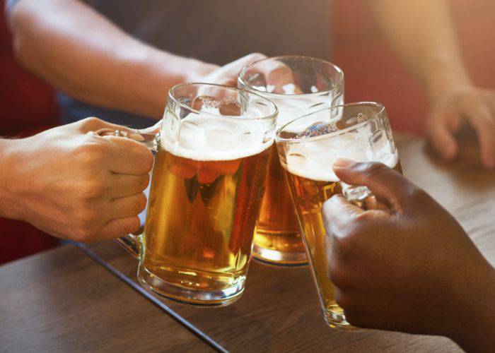 Three friends clinking their beer steins together.