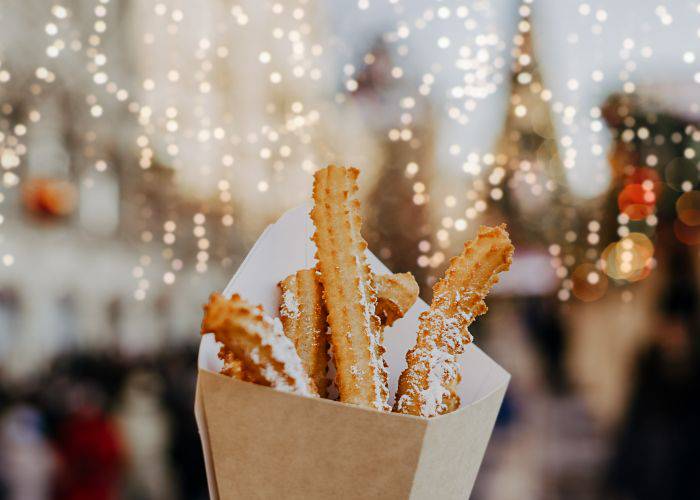 Sugar-coated churros in front of a background of festive lights.