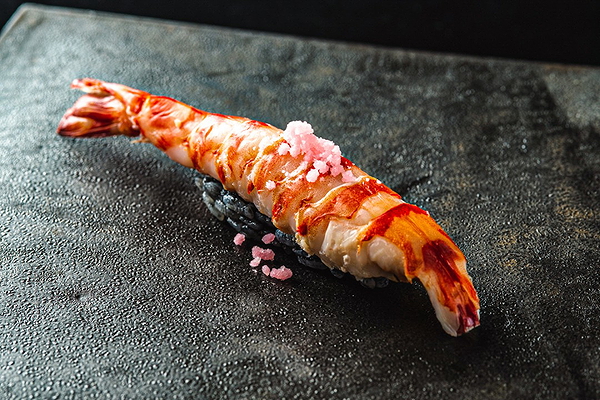 Gourmet shrimp sushi on a textured stone plate
