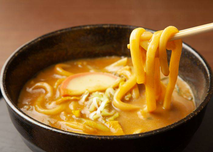 Someone eating a bowl of curry udon; the sauce looks thick and flavorful.