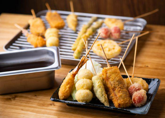 A selection of deep-fried skewers on a wire tray, perfect for catching excess oil.