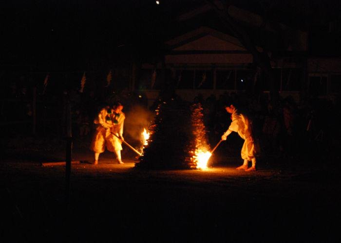 Two monks dressed in white lighting a bonfire