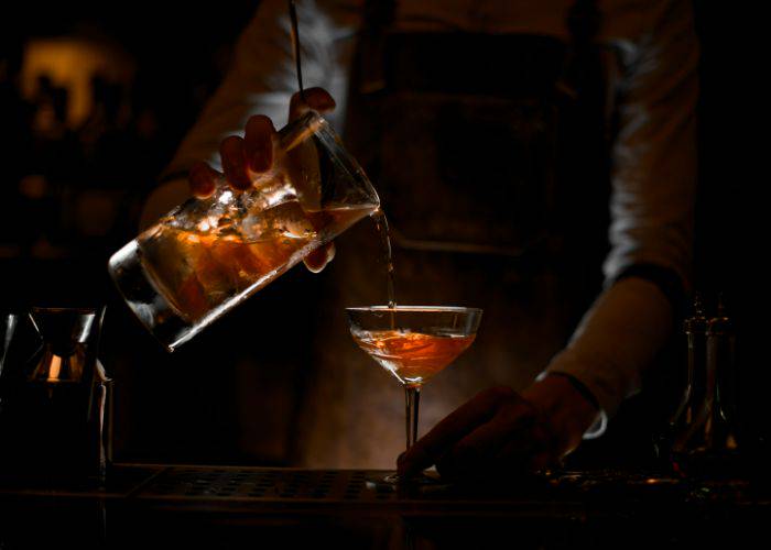 A cocktail being poured by an expert bartender.