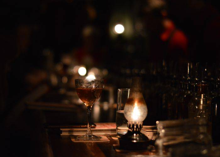 A moody, atmospheric bar lit by lanterns; nearby, a freshly made cocktail.