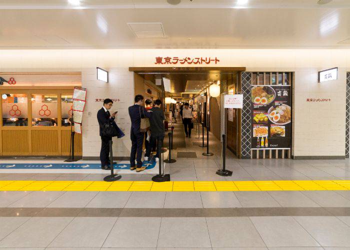 People lining up to enter a ramen restaurant in Tokyo Station Ramen Street.