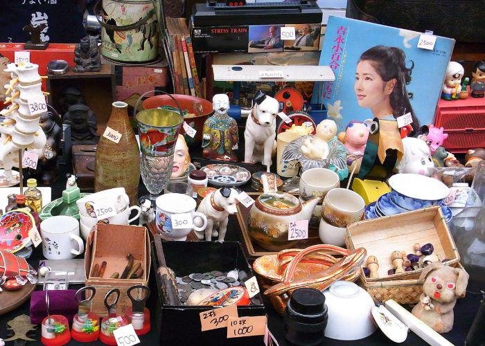 A table full of items such as mugs, plates and records at a flea market