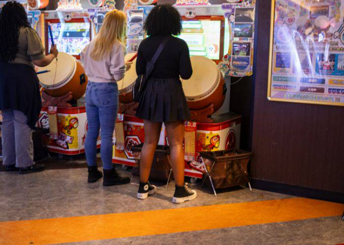 Friends drumming at a taiko drums arcade machine.