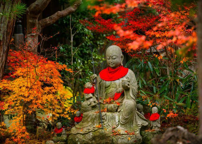 The famous Buddhist jizo statues, set against fall foliage.