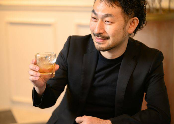 A man in a suit jacket drinking whisky.