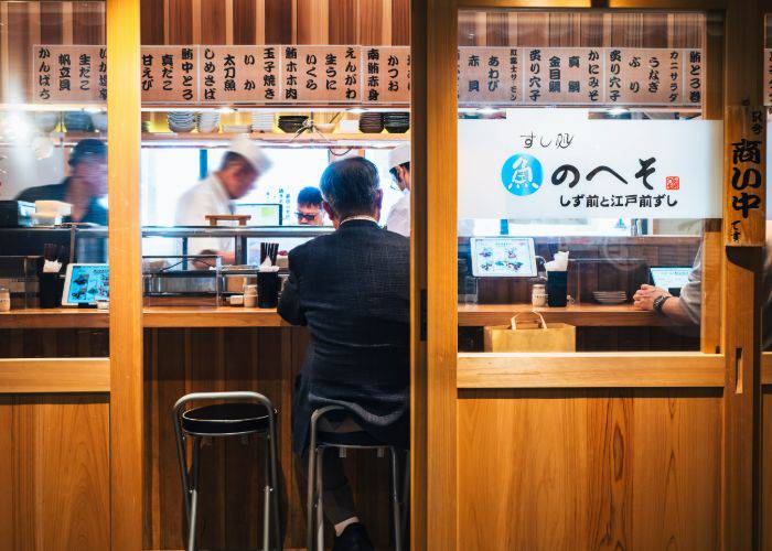 A man drinking alone at the counter of a small bar in Japan.