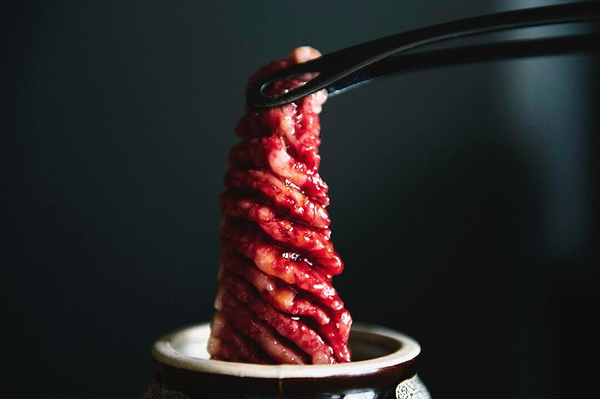 Freshly prepared wagyu beef slices lifted by chopsticks