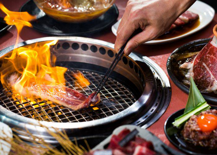 Someone grilling a slice of meat over a flame.