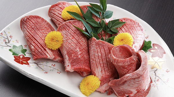 Sliced raw beef with garnishes on elegant serving plate