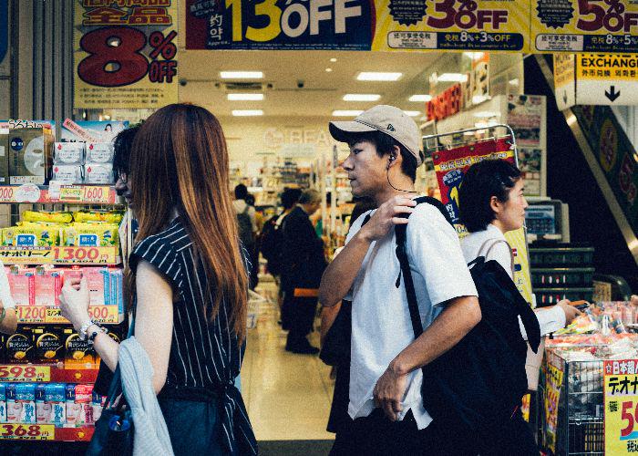 A man and a woman pass by a grocery store in Japan