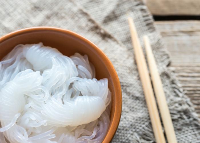 Jelly-like white noodles in a bowl next to wooden chopsticks