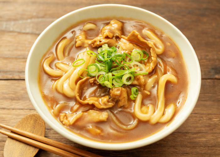 A hearty bowl of curry udon, topped with spring onion.