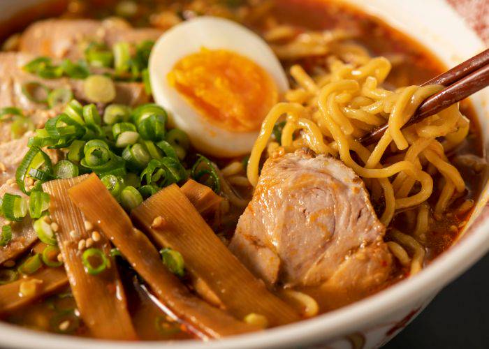 A close-up of a bowl of ramen, featuring pork, bamboo shoots, egg and more.