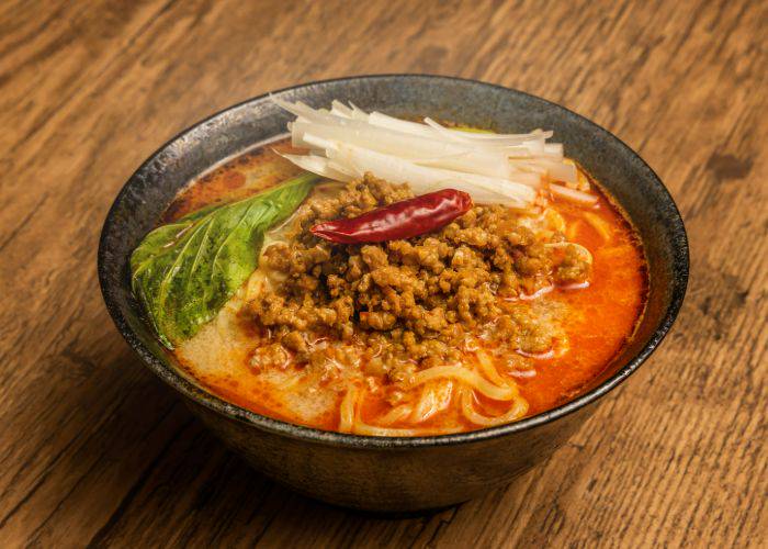 A bowl of tantan noodles, topped with beef and vegetables.