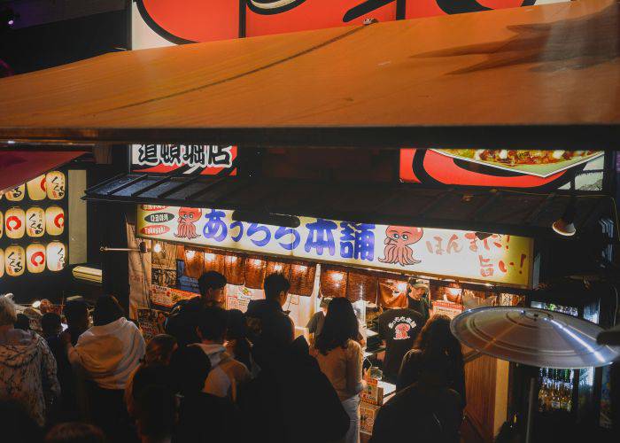 Guests lining up at night at the Dotonbori shop Takoyaki Juhachiban